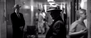 Movie still from “JFK” (1991), directed by Oliver Stone – A black and white photo of a man wearing a hat; Close Up shot, Over the shoulder angle