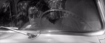 Movie still from “JFK” (1991), directed by Oliver Stone – A man sitting in the driver's seat of a car; Close Up shot, Over the shoulder angle