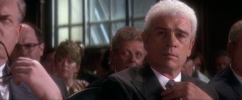 Movie still from “JFK” (1991), directed by Oliver Stone – A person wearing a suit and a tie; Close Up shot, Over the shoulder angle