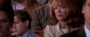 Movie still from “JFK” (1991), directed by Oliver Stone – A woman sitting next to a man in a crowd; Close Up shot, Low angle