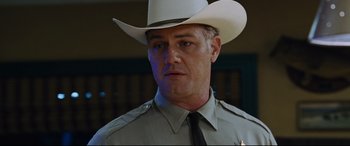 Movie still from “Jack Reacher: Never Go Back” (2016), directed by Edward Zwick – A man in a white cowboy hat is looking at the camera; Close Up shot, Low angle