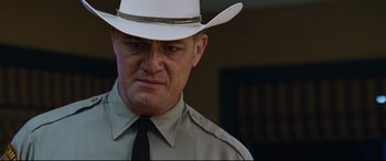 Movie still from “Jack Reacher: Never Go Back” (2016), directed by Edward Zwick – A man in a white hat and a black tie; Close Up shot, Low angle