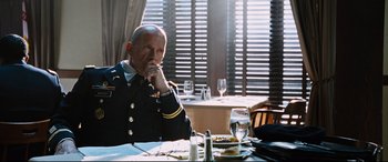 Movie still from “Jack Reacher: Never Go Back” (2016), directed by Edward Zwick – A man sitting at a table in front of a plate of food; Medium shot, Over the shoulder angle