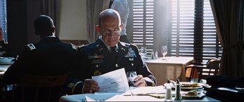 Movie still from “Jack Reacher: Never Go Back” (2016), directed by Edward Zwick – A man in a military uniform sitting at a table; Medium shot, Low angle