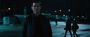 Movie still from “Jack Reacher: Never Go Back” (2016), directed by Edward Zwick – A man standing in a parking lot at night; Medium shot, Over the shoulder angle