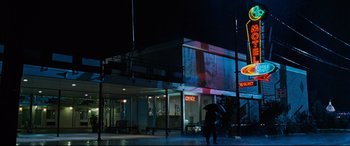 Movie still from “Jack Reacher: Never Go Back” (2016), directed by Edward Zwick – Two people walking down the street at night with an umbrella; Extreme Wide shot, Low angle