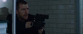 Movie still from “Jack Reacher: Never Go Back” (2016), directed by Edward Zwick – A man holding a gun while wearing black gloves; Close Up shot, Low angle