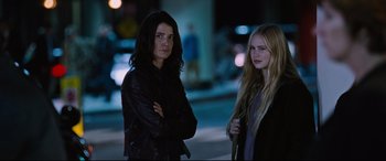 Movie still from “Jack Reacher: Never Go Back” (2016), directed by Edward Zwick – Two women standing next to each other on the sidewalk; Medium shot, Over the shoulder angle