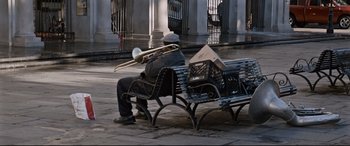 Movie still from “Jack Reacher: Never Go Back” (2016), directed by Edward Zwick – A man sitting on top of a park bench with a trombone; Wide shot, Low angle