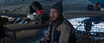 Movie still from “Jack Reacher: Never Go Back” (2016), directed by Edward Zwick – A homeless man sitting on the ground in the dark; Medium shot, High angle