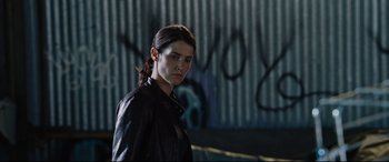 Movie still from “Jack Reacher: Never Go Back” (2016), directed by Edward Zwick – A woman in a leather jacket standing next to a wall; Close Up shot, Low angle