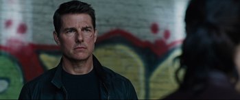 Movie still from “Jack Reacher: Never Go Back” (2016), directed by Edward Zwick – A man in a black jacket standing in front of a wall; Close Up shot, Over the shoulder angle