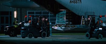 Movie still from “Jack Reacher: Never Go Back” (2016), directed by Edward Zwick – A forklift is parked in front of an airplane; Extreme Wide shot, Low angle