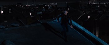 Movie still from “Jack Reacher: Never Go Back” (2016), directed by Edward Zwick – A woman is running on a rooftop at night; Wide shot, Overhead angle