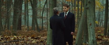 Movie still from “Jack Ryan: Shadow Recruit” (2014), directed by Kenneth Branagh – Two men in suits are talking in the woods; Medium shot, Over the shoulder angle