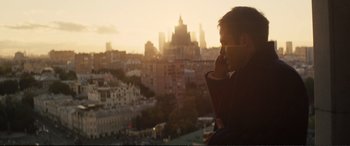 Movie still from “Jack Ryan: Shadow Recruit” (2014), directed by Kenneth Branagh – A man talking on a cell phone in front of a city skyline; Medium shot, Over the shoulder angle