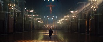 A man in a suit walks through an empty cathedral