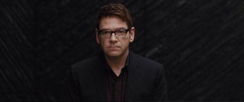 Movie still from “Jack Ryan: Shadow Recruit” (2014), directed by Kenneth Branagh – A person wearing glasses and a suit; Close Up shot, Over the shoulder angle