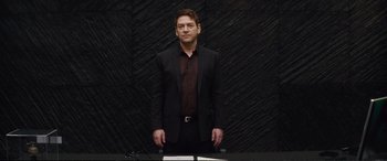 Movie still from “Jack Ryan: Shadow Recruit” (2014), directed by Kenneth Branagh – A man in a black suit standing in front of a black wall; Medium shot, Low angle