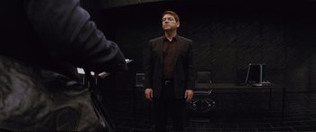 Movie still from “Jack Ryan: Shadow Recruit” (2014), directed by Kenneth Branagh – A man in a black suit standing in front of a camera; Medium shot, Over the shoulder angle