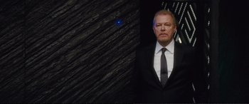 Movie still from “Jack Ryan: Shadow Recruit” (2014), directed by Kenneth Branagh – A man wearing a suit and tie standing in front of a wall; Medium shot, Low angle