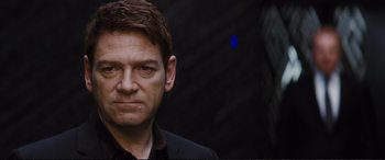 Movie still from “Jack Ryan: Shadow Recruit” (2014), directed by Kenneth Branagh – A person wearing a suit and tie; Close Up shot, Over the shoulder angle