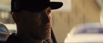 Movie still from “Jack Ryan: Shadow Recruit” (2014), directed by Kenneth Branagh – A person wearing a hat looking to the side; Close Up shot, Over the shoulder angle