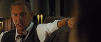 Movie still from “Jack Ryan: Shadow Recruit” (2014), directed by Kenneth Branagh – A man sitting on a couch holding a remote control; Close Up shot, Over the shoulder angle