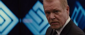 Movie still from “Jack Ryan: Shadow Recruit” (2014), directed by Kenneth Branagh – A man with a beard and a suit and tie looking at the camera; Close Up shot, Over the shoulder angle