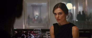 Movie still from “Jack Ryan: Shadow Recruit” (2014), directed by Kenneth Branagh – A woman sitting at a table with a glass of wine; Close Up shot, Over the shoulder angle