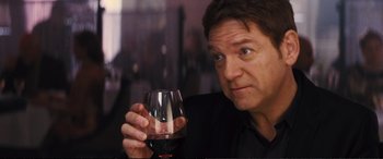 Movie still from “Jack Ryan: Shadow Recruit” (2014), directed by Kenneth Branagh – A person holding a glass of red wine; Close Up shot, Over the shoulder angle