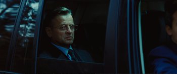 Movie still from “Jack Ryan: Shadow Recruit” (2014), directed by Kenneth Branagh – A man in a suit and tie sitting in a car; Close Up shot, Over the shoulder angle