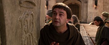 Movie still from “Jack the Giant Slayer” (2013), directed by Bryan Singer – A man wearing a brown robe and a brown hat; Close Up shot, Over the shoulder angle