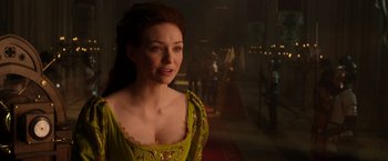 Movie still from “Jack the Giant Slayer” (2013), directed by Bryan Singer – A woman in a yellow dress standing next to a red carpet; Close Up shot, Over the shoulder angle