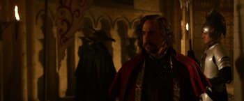 Movie still from “Jack the Giant Slayer” (2013), directed by Bryan Singer – A man with a long beard and a red cape; Medium shot, Over the shoulder angle