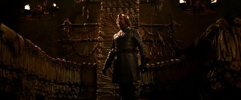 Movie still from “Jack the Giant Slayer” (2013), directed by Bryan Singer – A man dressed in medieval garb standing in front of a wall of skulls; Wide shot, Low angle