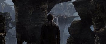 Movie still from “Jack the Giant Slayer” (2013), directed by Bryan Singer – A man standing in front of a waterfall in the mountains; Wide shot, Over the shoulder angle