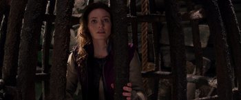 Movie still from “Jack the Giant Slayer” (2013), directed by Bryan Singer – A woman holding onto a pole in a dark room; Medium shot, Over the shoulder angle