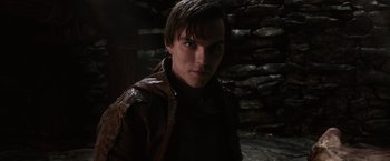 Movie still from “Jack the Giant Slayer” (2013), directed by Bryan Singer – A man in a brown jacket standing in front of a stone wall; Close Up shot, Low angle