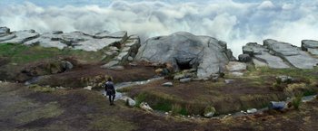 Movie still from “Jack the Giant Slayer” (2013), directed by Bryan Singer – A person is walking on a path near a rock formation; Extreme Wide shot, High angle