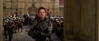 Movie still from “Jack the Giant Slayer” (2013), directed by Bryan Singer – A man dressed as a medieval knight in front of a crowd of people; Medium shot, Over the shoulder angle
