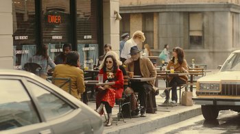 Movie still from “Jackass Forever” (2022), directed by Jeff Tremaine – A group of people sitting at a table outside; Wide shot, High angle