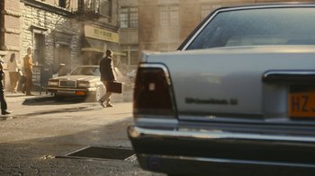 Movie still from “Jackass Forever” (2022), directed by Jeff Tremaine – A man walking down the street carrying a suitcase; Wide shot, Over the shoulder angle