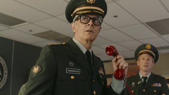 Movie still from “Jackass Forever” (2022), directed by Jeff Tremaine – A man in a military uniform holding a red phone; Medium shot, Low angle
