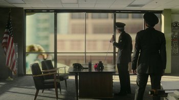 Movie still from “Jackass Forever” (2022), directed by Jeff Tremaine – A man in a uniform standing in front of a large window; Extreme Wide shot, High angle