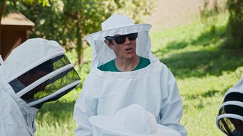 Movie still from “Jackass Forever” (2022), directed by Jeff Tremaine – A man in a beekeeper's suit and a hat; Medium shot, Over the shoulder angle