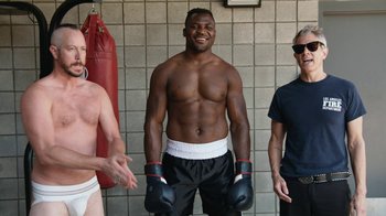 Movie still from “Jackass Forever” (2022), directed by Jeff Tremaine – Three boxers are posing for a picture in a gym; Medium shot, High angle