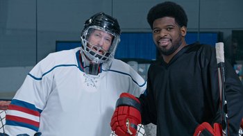 Movie still from “Jackass Forever” (2022), directed by Jeff Tremaine – Two men are posing for a picture while wearing hockey gear; Medium shot, High angle