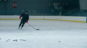 Movie still from “Jackass Forever” (2022), directed by Jeff Tremaine – A man on a hockey rink with a hockey stick; Wide shot, High angle
