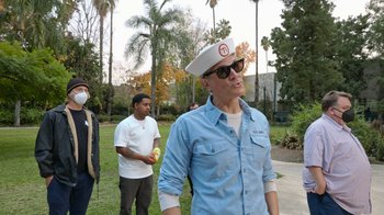 Movie still from “Jackass Forever” (2022), directed by Jeff Tremaine – A group of men standing on a lush green field; Medium shot, Over the shoulder angle